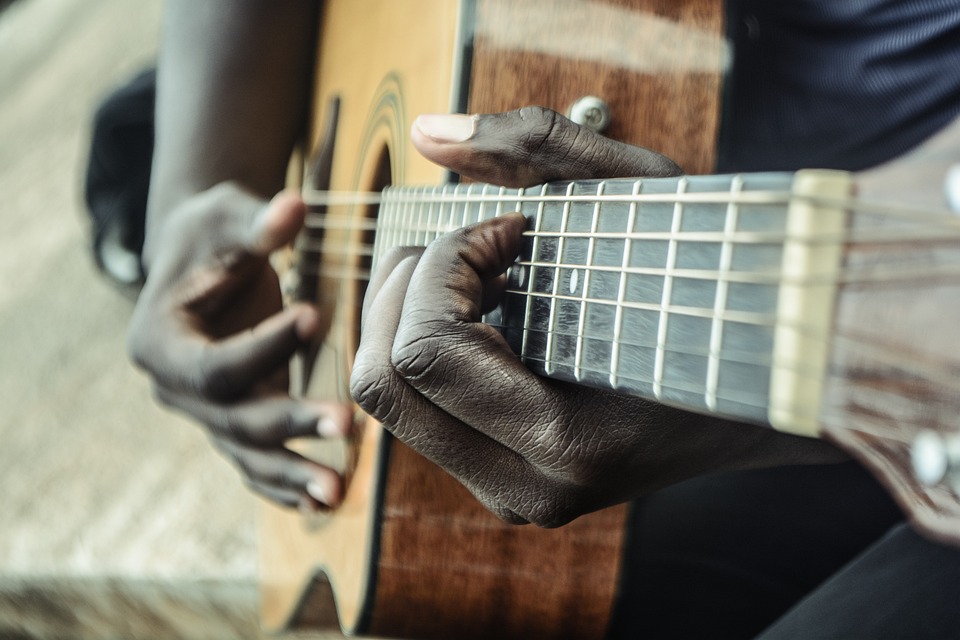 On voit les mains d'un homme en train de jouer de la guitare